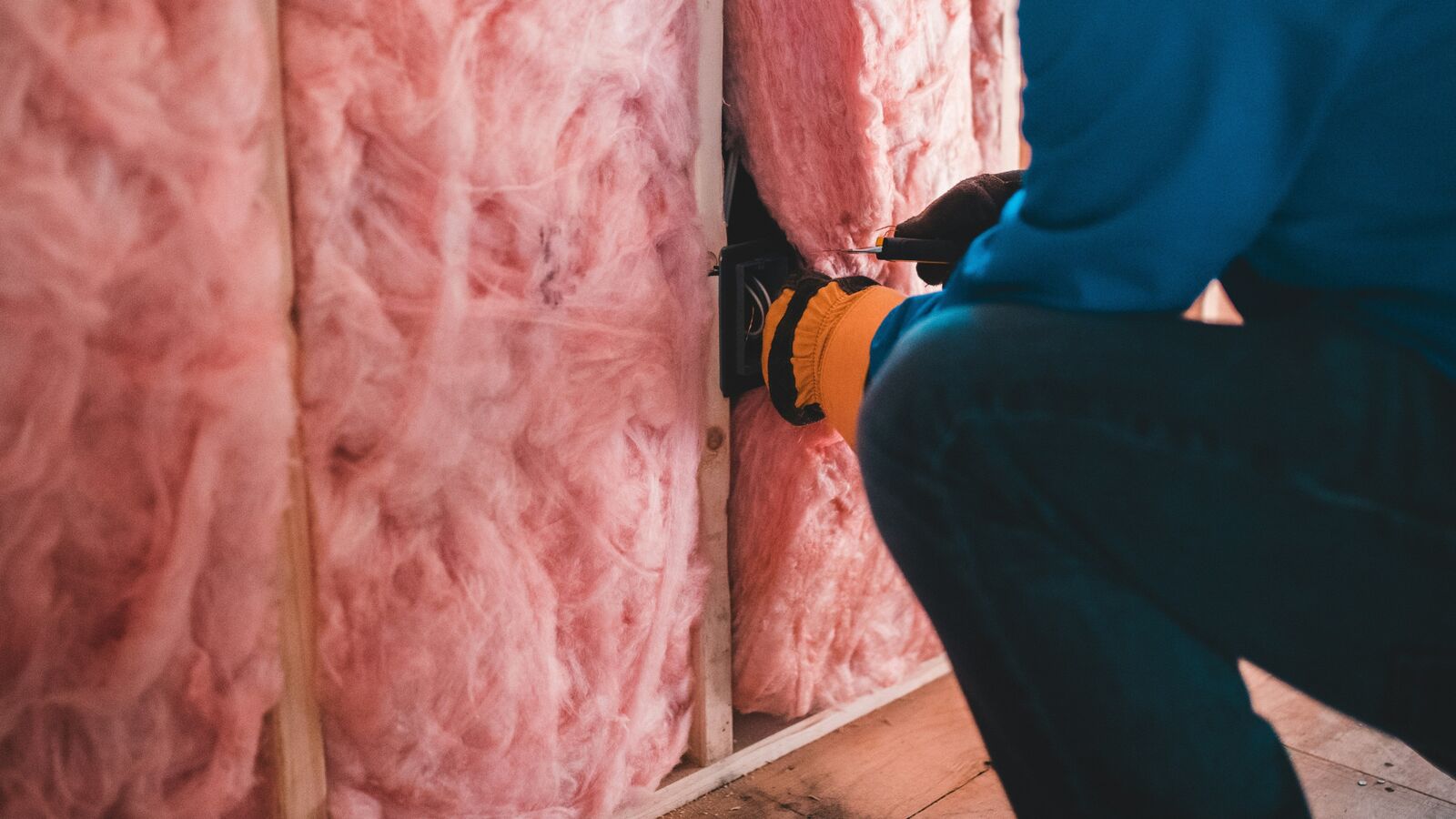 Professional insulation installer fitting Pink Batts glass wool insulation in a home